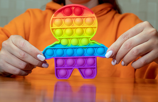 In the hands of women, a touch-sensitive pop it toy. Relieving stress and anxiety. A trendy fussy game for stressed kids and adults alike. Selective focus.