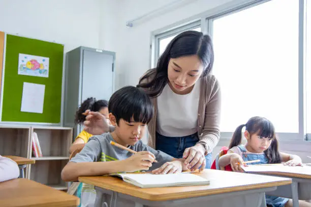 Photo of The girl and boy student Take note lecture in the classroom. Young woman teachers give advice on learning to Diversity elementary school children. back to School concept