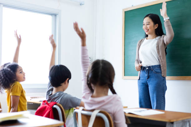 istock Diversity of elementary school students raise their hands to answer teacher questions in class room. Back to school concept 1320972283
