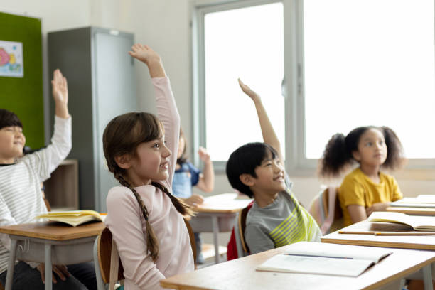 istock Diversity of elementary school students raise their hands to answer teacher questions. Back to school concept 1320972297