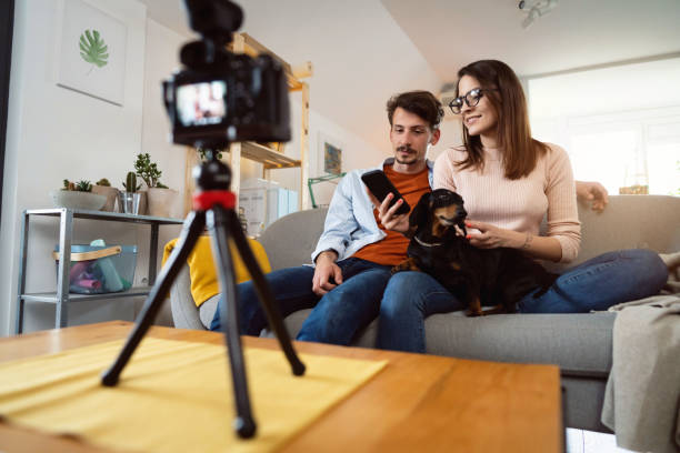 istock Low-angle view of young smiling couple recording video tutorial at home 1320972423