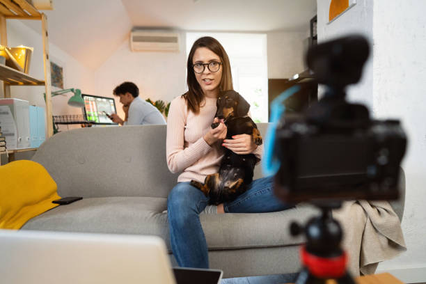 istock Young female vlogger recording video tutorial while holding her dog at home 1320972513