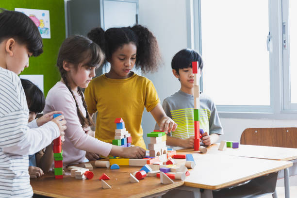 group of Diversity of school students playing wooden blocks in classroom. Elementary school children enjoy learning together. Learn to work as a team. Back to school concept stock photo