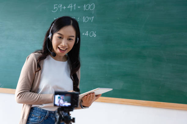 Cheerful young asian woman teacher Teach online. tutor coach looking at webcam and talking in classroom giving virtual teaching remote class online. Modern education remotely. stock photo