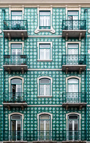 Architectural detail close-up of traditional green tile wall facade of apartment building with cast iron railing balconies in Lisbon Portugal