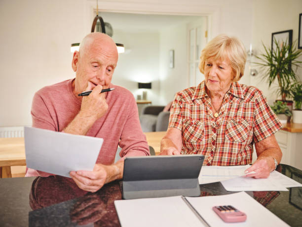 istock Shot of a senior couple using a digital tablet while through paperwork together at home 1320976212
