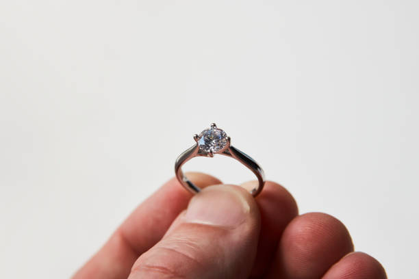 istock Man's hand giving engagement ring over white background 1320977395