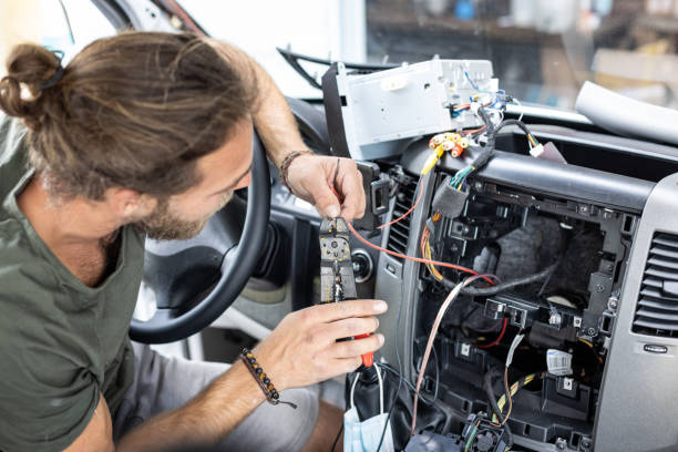 Man working on electronics inside a van Man working on electronics inside the center console of a van. wire cutter stock pictures, royalty-free photos & images