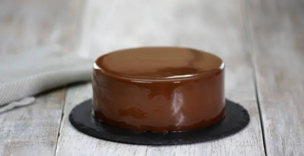 Photo of The mousse cake is decorated with chocolate mirror glaze. Modern dessert.