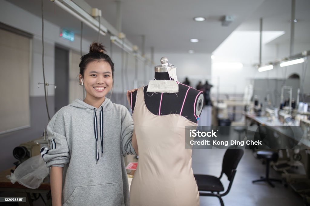 Asian Chinese female fashion college student doing clothing project at college workshop. Smiling facing camera Fashion Stock Photo