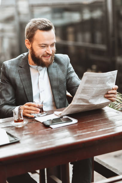 istock Smiling Elegant Male Looking For Hiring Advertisements In Newspaper 1320983976