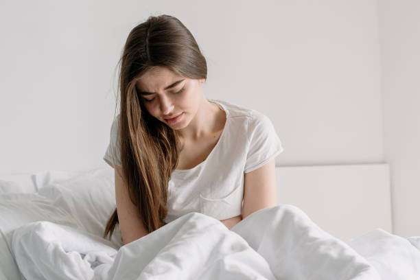 istock Sick young woman sit on bed touch stomach 1320984008