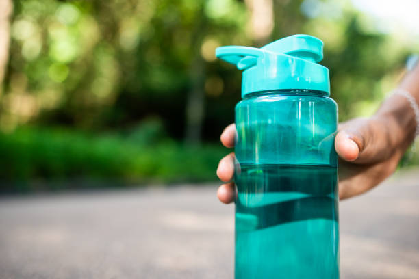 Woman holding plastic bottle of water.