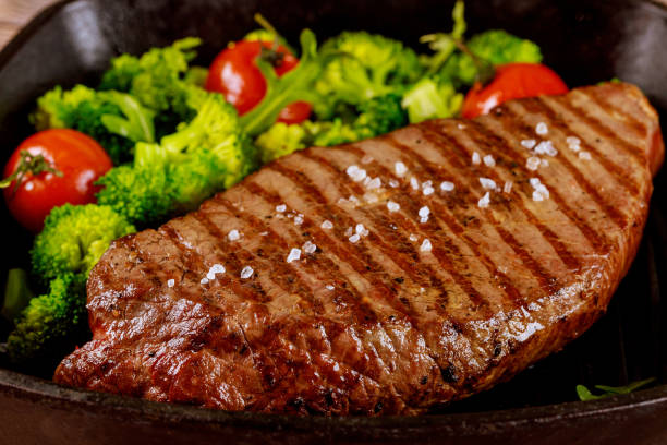 istock Grilled medium rare beef steak with broccoli and tomato on grill pan. 1320986505