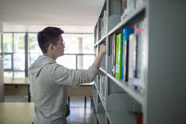 istock Asian university student searching references book studying in library 1320987835