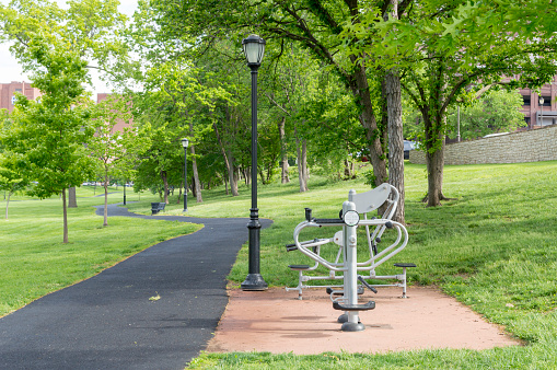 This shot shows a public park in the midwestern United States. The park is surrounded by green trees and contains exercise equipment available to any fitness enthusiast.