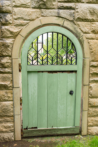 This shot shows a decorative green door set in a stone wall.  The wall surrounds a beautiful secret garden.