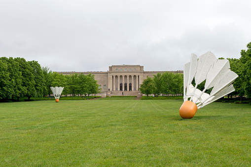 May 18, 2021 - Kansas City, Missouri, USA: This shot shows the expansive lawn and stately entrance on the south side of the Nelson-Atkins Museum in Kansas City, Missouri.  This distinctive landmark features giant shuttlecock birdies on the lawn as part of the imaginative landscaping.  This shot was taken on a rainy spring day with clouds in the background.