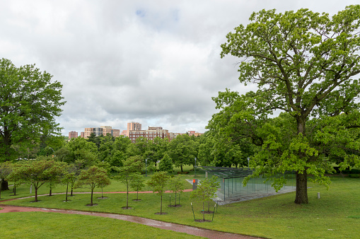 May 18, 2021 - Kansas City, Missouri, USA: This shot shows the glass labyrinth that is part of the sculpture garden on the south side of the Nelson-Atkins Museum in Kansas City, Missouri.  This distinctive landmark is a centerpiece for the city.  In the background are some of the buildings that make up part of the city skyline.  This shot was taken on a rainy spring day with clouds in the background and the landscaping a lush shade of green.