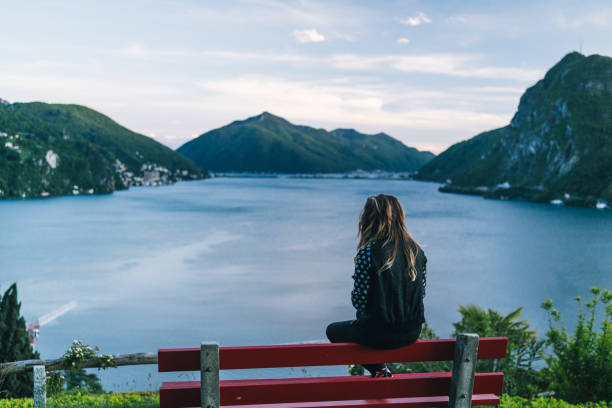 istock Young woman relaxes on bench at lakefront viewpoint 1320993292
