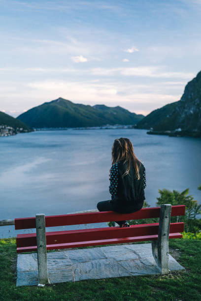 istock Young woman relaxes on bench at lakefront viewpoint 1320993293