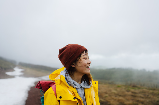 Photo of a young Asian woman in the nature on a cold, foggy day