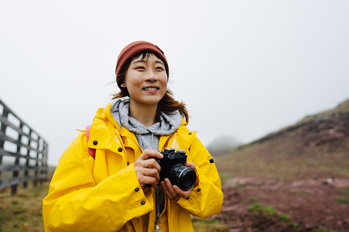 Photo of a young, smiling Asian woman with a camera during the hike