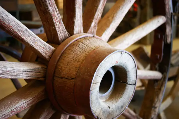Photo of Antique Wagon Wheel Selectively Focused Accentuating Dry Splitting Wood and Rusty Metal Bands on Bright Summer Day