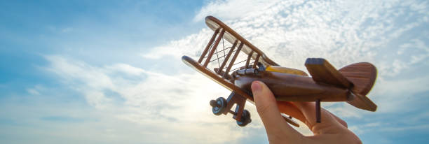 istock The hand with a wooden plane on the blue sky background 1320999670