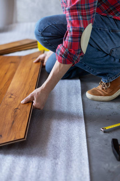 istock Man worker installing laminate flooring. Wooden laminate floor plank and tools 1321000908