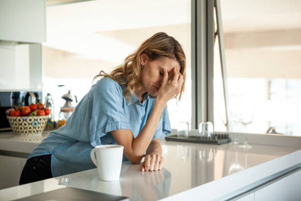 istock Stressed woman holding her face in her hand while leaning against kitchen counter during daytime 1321004611