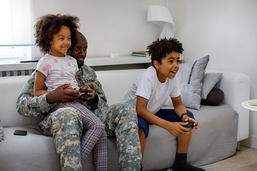 Army father and his children competing in video games at home