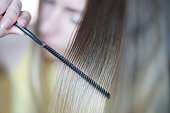 A lock of hair shatush close-up. The process of combing with a thin black comb