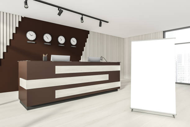 istock Empty office, wooden reception interior at white wall, 4 clocks on it. Panoramic window. Hotel check in desk. Blank roll-up banner. 1321007560