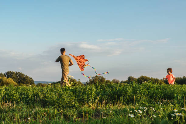 istock Happy family flying a kite in field. 1321008208