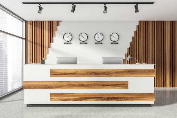 istock Empty office, wooden reception interior at white wall, 4 clocks on it. Panoramic window. Hotel check in desk. 1321010385