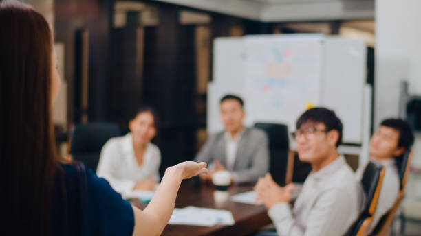 uomini d'affari e imprenditrici che incontrano idee di brainstorming che conducono colleghi di progetto di presentazione aziendale lavorando insieme pianificare la strategia di successo godono del lavoro di squadra nell'ufficio notturno. - japanese ethnicity women asian and indian ethnicities female foto e immagini stock