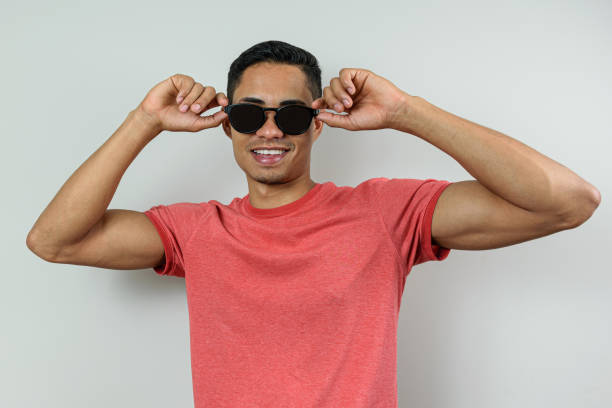 smiling brazilian, 28 years old, wearing a pink shirt and putting his sunglasses on his face. - beautiful men young adult 25 30 years imagens e fotografias de stock