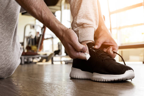istock Unrecognizable young man tying his shoelaces in a gym 1321012694