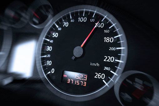 The speedometer of a modern car shows a high driving speed. Added motion blur.