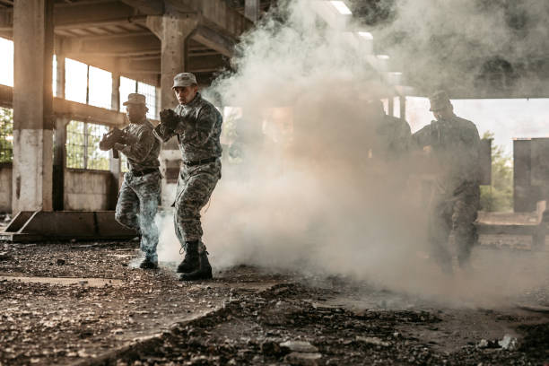 Group of soldiers with shotguns running at battlefield through smoke in a ruined building.