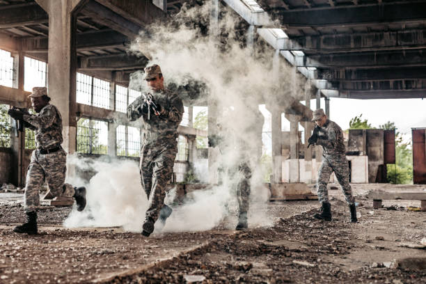 Group of soldiers with shotguns running at battlefield through smoke in a ruined building.