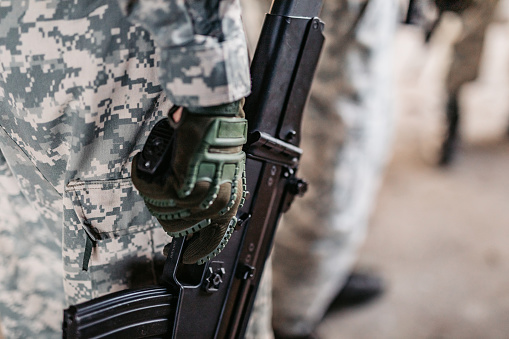 Soldier holding weapon with finger on trigger, close up.