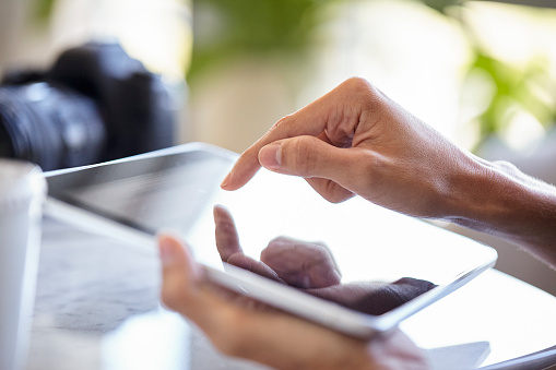 Close up of young woman´s hands using touchscreen device at workplace