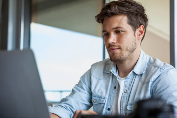 istock Focused male photographer working on laptop during daytime 1321017892