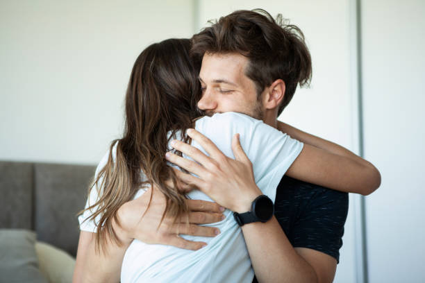 Smiling young couple embracing in bedroom Young heterosexual couple hugging each other while in bedroom during daytime miscarriage stock pictures, royalty-free photos & images