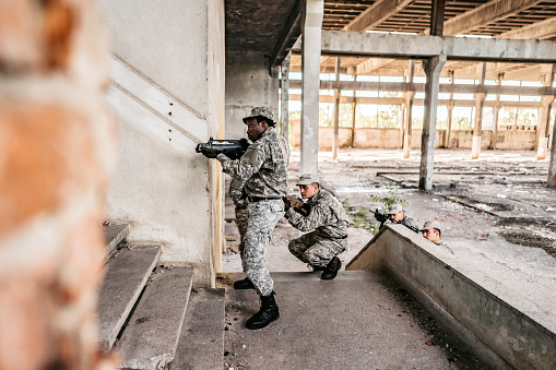 Military assault team stalking on staircase in abandoned building.