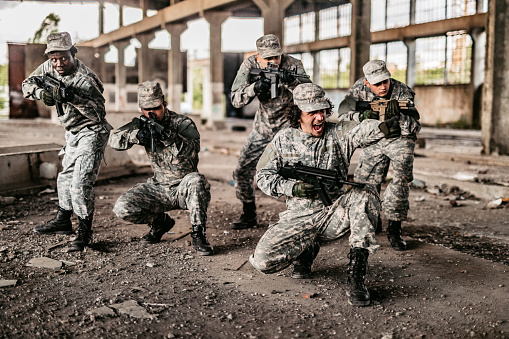 Small military assault team charging in battle in abandoned building.