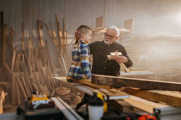 istock Boy and his grandfather in carpenter workshop 1321019111