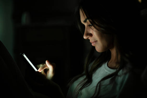 istock Side view of young woman text messaging while leaning against the bed during night time 1321019852